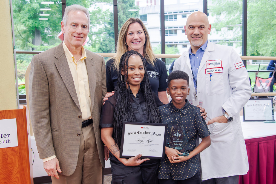 Unique Myatt, Housekeeping Group Leader, Environmental Services, Fox Chase (center) with her son and (from left) Jonathan Chernoff, MD, PhD, Cancer Center Director; presenting speaker Nicole Seeley; and Fox Chase President and CEO Robert Uzzo, MD, MBA, FACS.