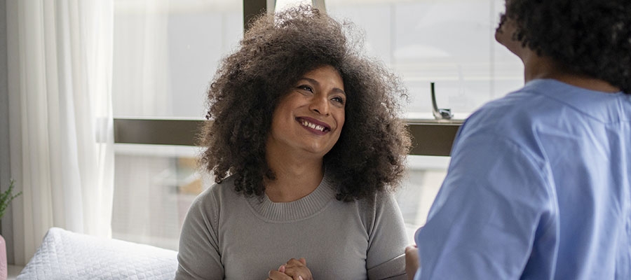 trans-femme patient smiling, talking with nurse