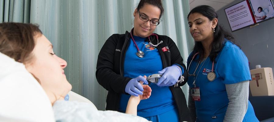 Two nurses checking a patients blood sugar