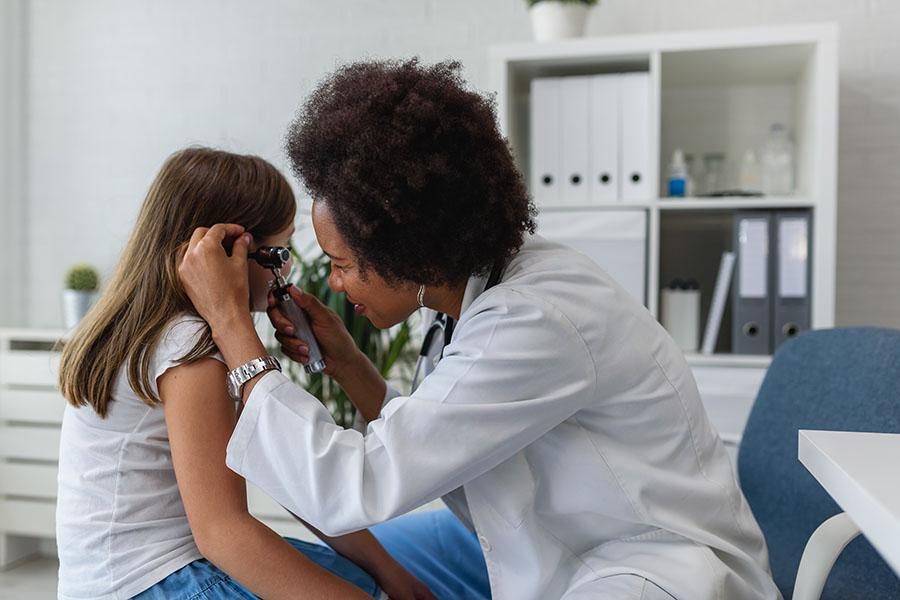 Doctor checking young patient's ear with otoscope