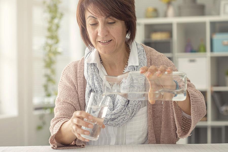Woman pouring a glass of water in her kitchen