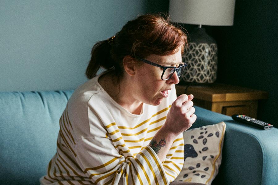 Woman coughing while making a fist