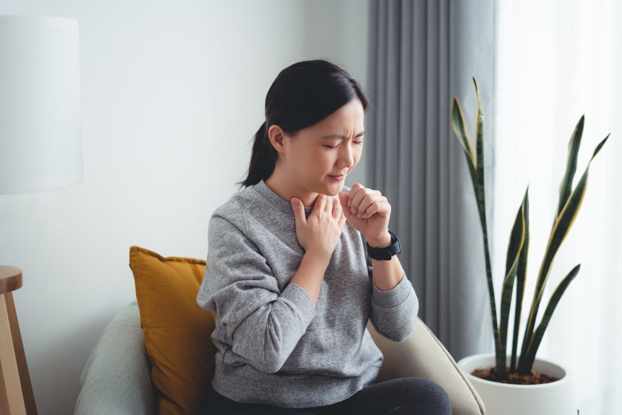 Woman holding chest and coughing