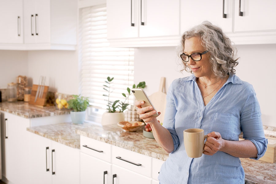 Older woman looking at her phone in the kitchen