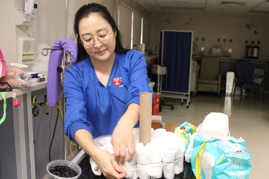 Baek uses a cardboard paper towel roll and a rubber band to secure the base of one of her diaper cakes.
