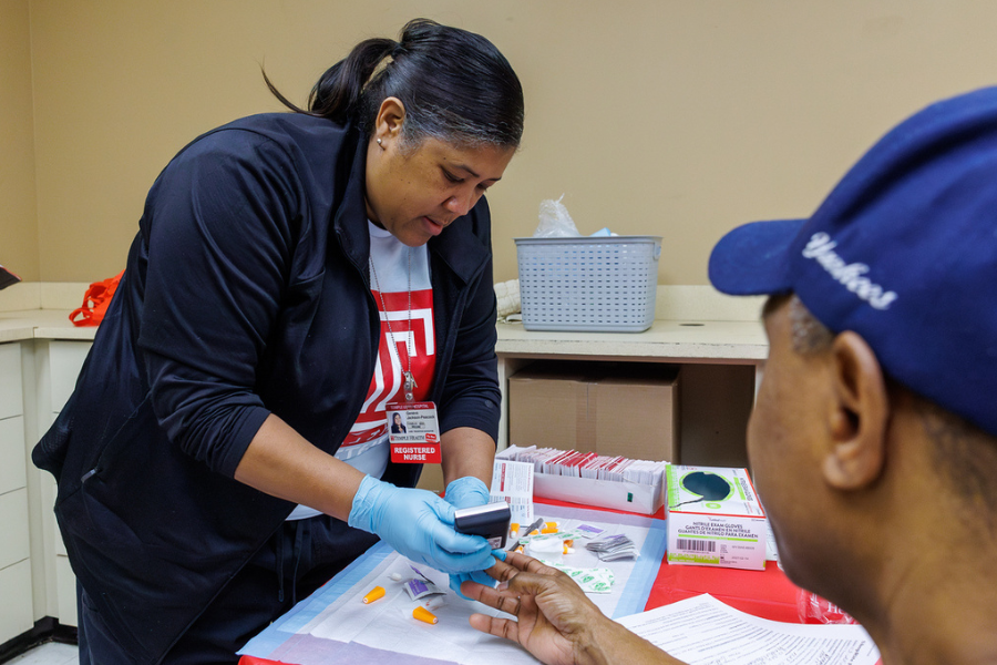 A Temple Health RN performs an A1C check on a community member.