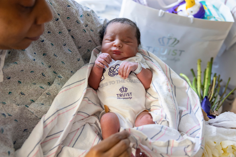 One of the babies born at Temple Health during tournament week that golfer Tony Finau and his wife Alana visited, wearing a gifted Truist Championship onesie.  