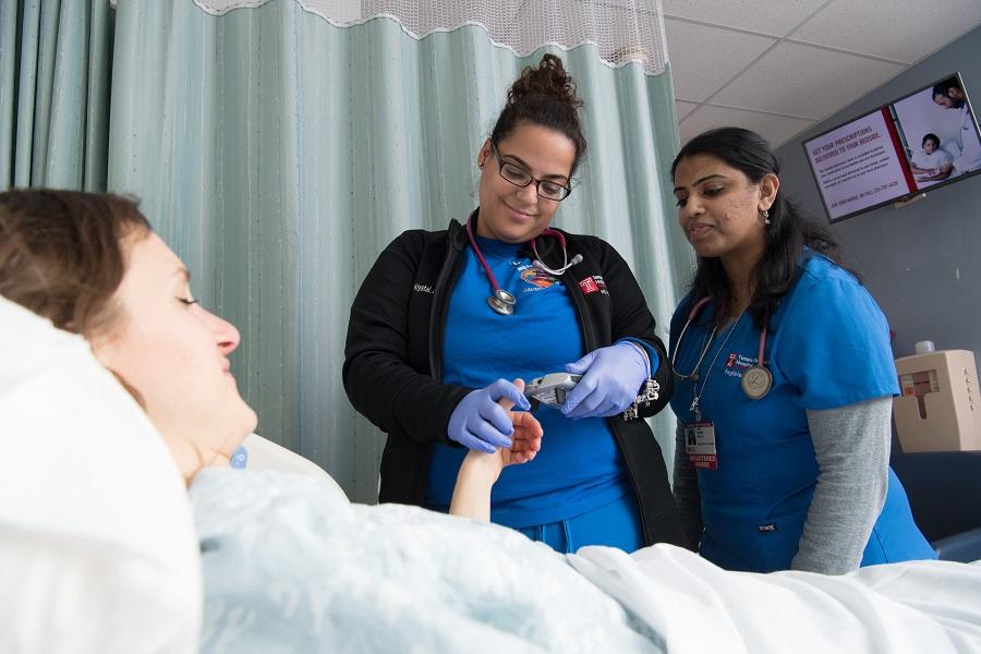 Two nurses checking a patients blood sugar