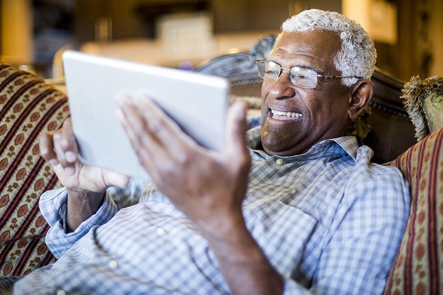Elderly man on a couch with a tablet