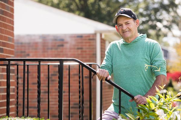 Kidney transplant patient, George P., holding stair railing outside