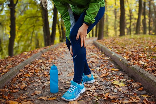 Runner holding sore knee on trail
