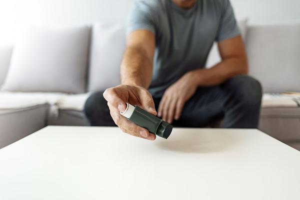 Man reaching for his inhaler on the table