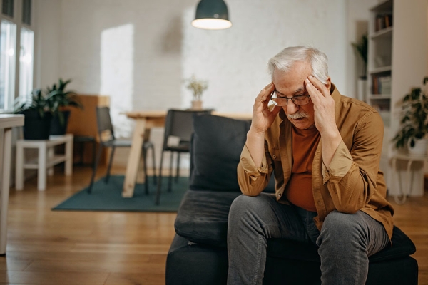 Man stressed holding his head on the couch