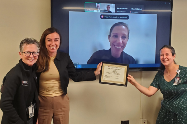 Dr. Rachel Snyder (center, on screen) receives her TFP Kudos Award from Amy J. Goldberg, MD, FACS, The Marjorie Joy Katz Dean of the Lewis Katz School of Medicine (far left) and Claire Raab, MD, President & CEO of Temple Faculty Physicians (second from left). Dr. Jaime Fineman (far right) is also pictured. 