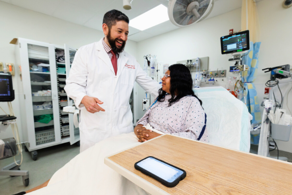 Dr. Benjamin Slovis, TUH’s Chief Medical Information Officer, speaks to a patient while DAX records and processes the conversation on his phone.